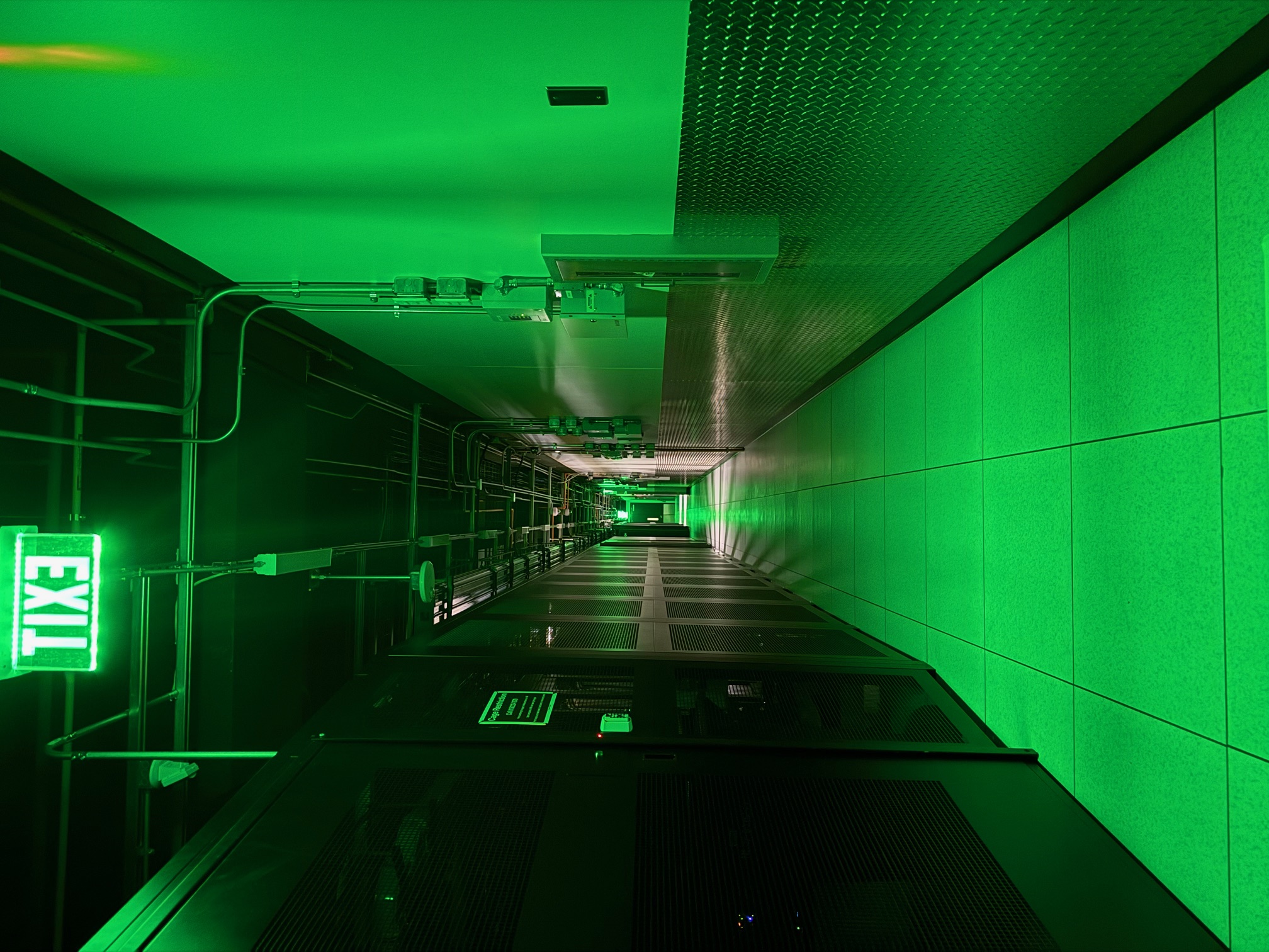 Data center corridor illuminated by green emergency exit lighting